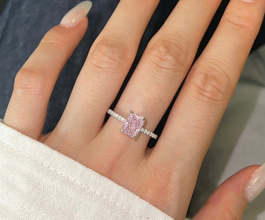 Hand wearing a pink diamond ring with a neutral background