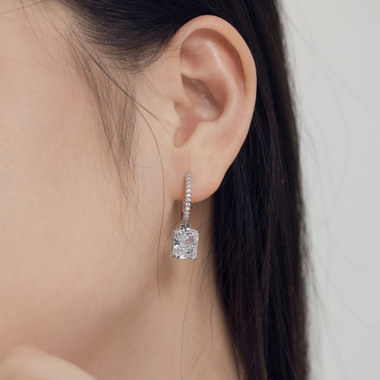 Close-up of an ear wearing a diamond earring with a blurred background