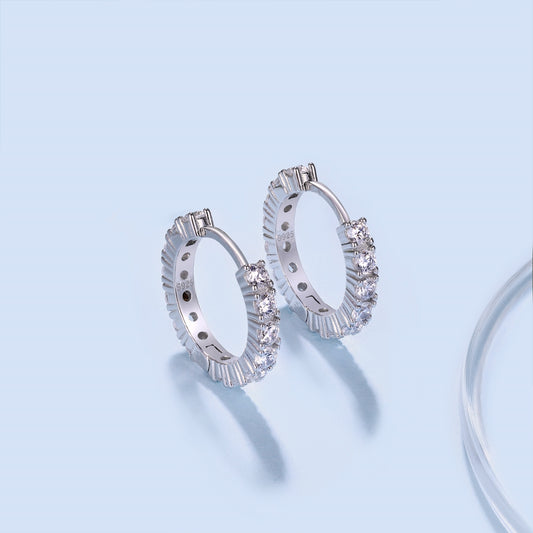 Silver hoop earrings with clear gemstones on a light blue background