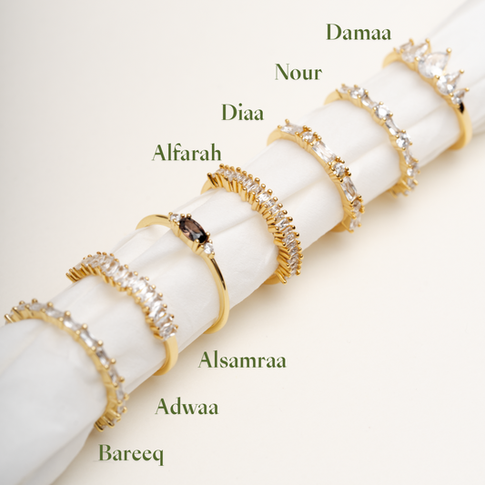 Stackable gold plated CZ rings collection featuring Bareeq, Nour, Damaa, Alfarah designs on white background - Luméra Designs Kuwait luxury jewelry