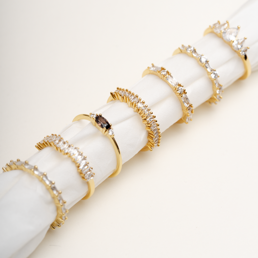 Stackable gold plated CZ rings collection featuring Bareeq, Nour, Damaa, Alfarah designs on white background - Luméra Designs Kuwait luxury jewelry